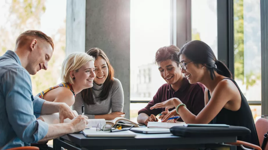 Group of university students discussing their work while sat at a table